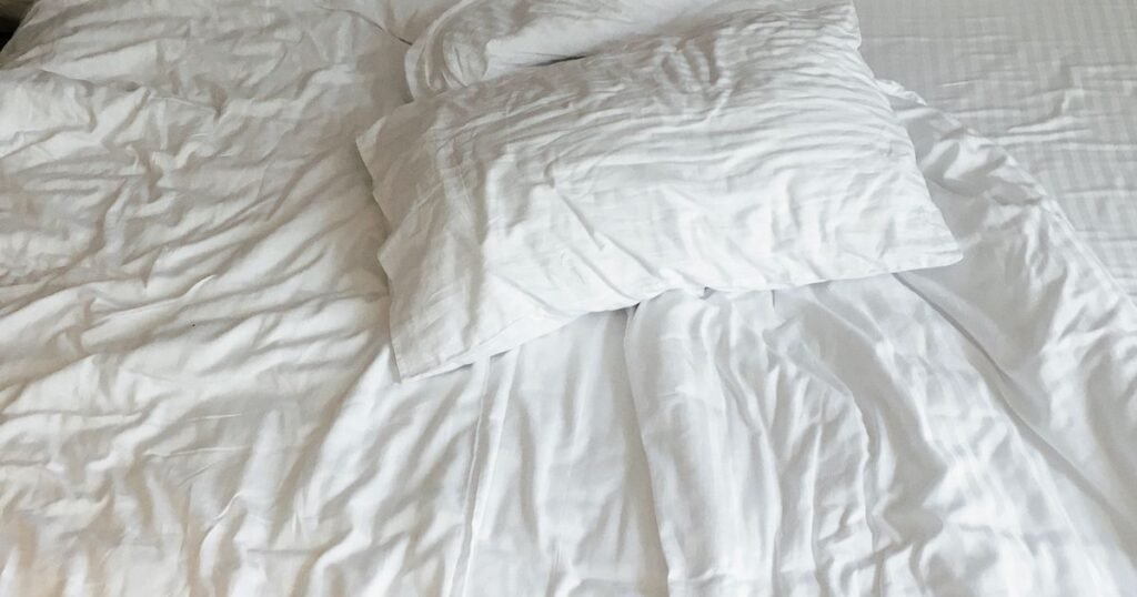 Fresh white hotel bed linens and pillows, Denver hotel laundry service